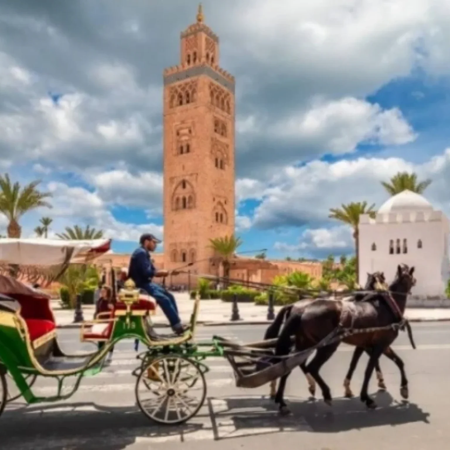 A vibrant sunset casting golden hues over the windswept sand dunes in Merzouga, with silhouettes of visitors riding camels, embarking on a 2 days tour From Marrakech to zagora desert tour