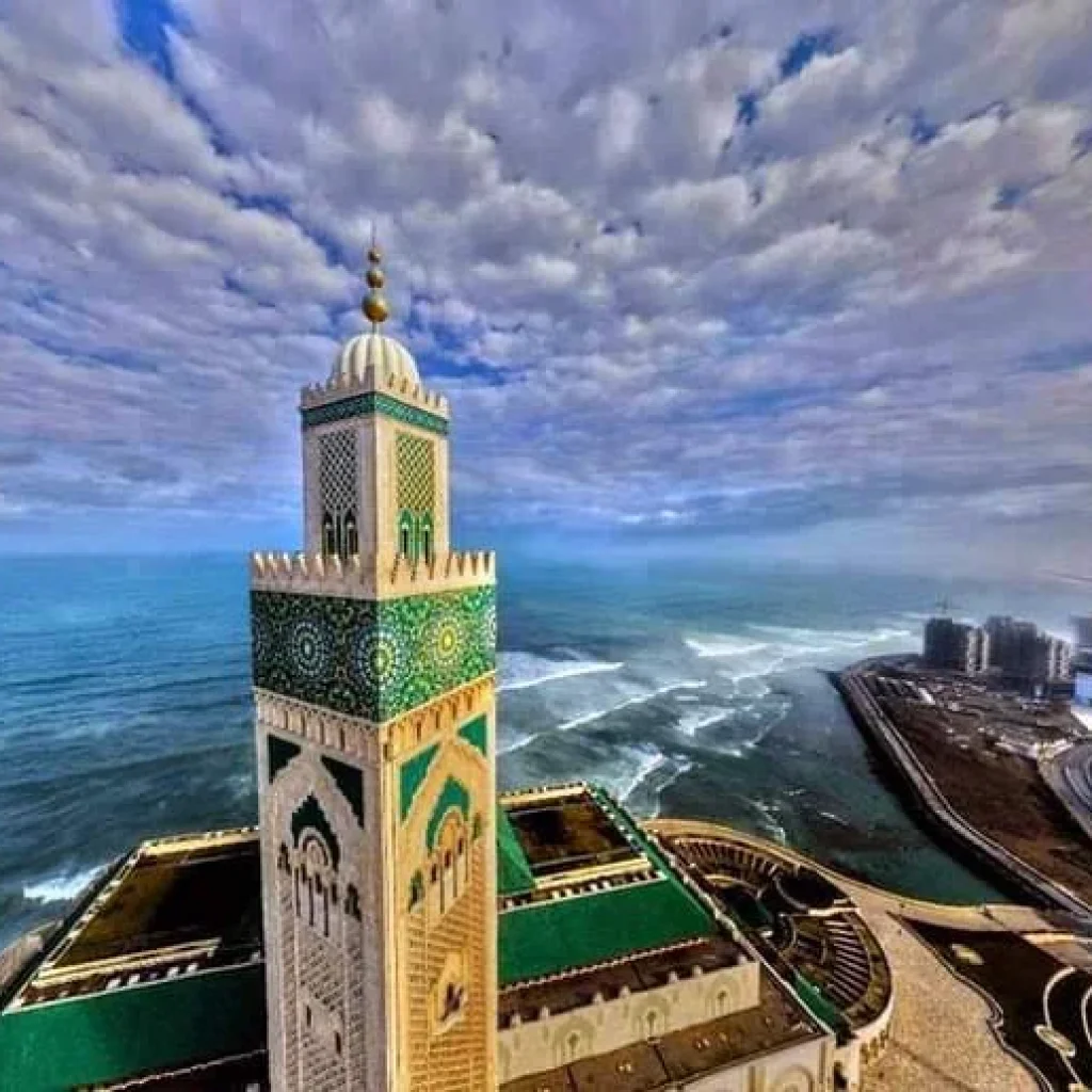 10 days tour from casablanca Spectacular view of the Hassan II Mosque in Casablanca, with its towering minaret overlooking the Atlantic Ocean under a clear blue sky