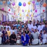 Community of Moroccan people celebrating Eid Al Fitr in a decorated street.